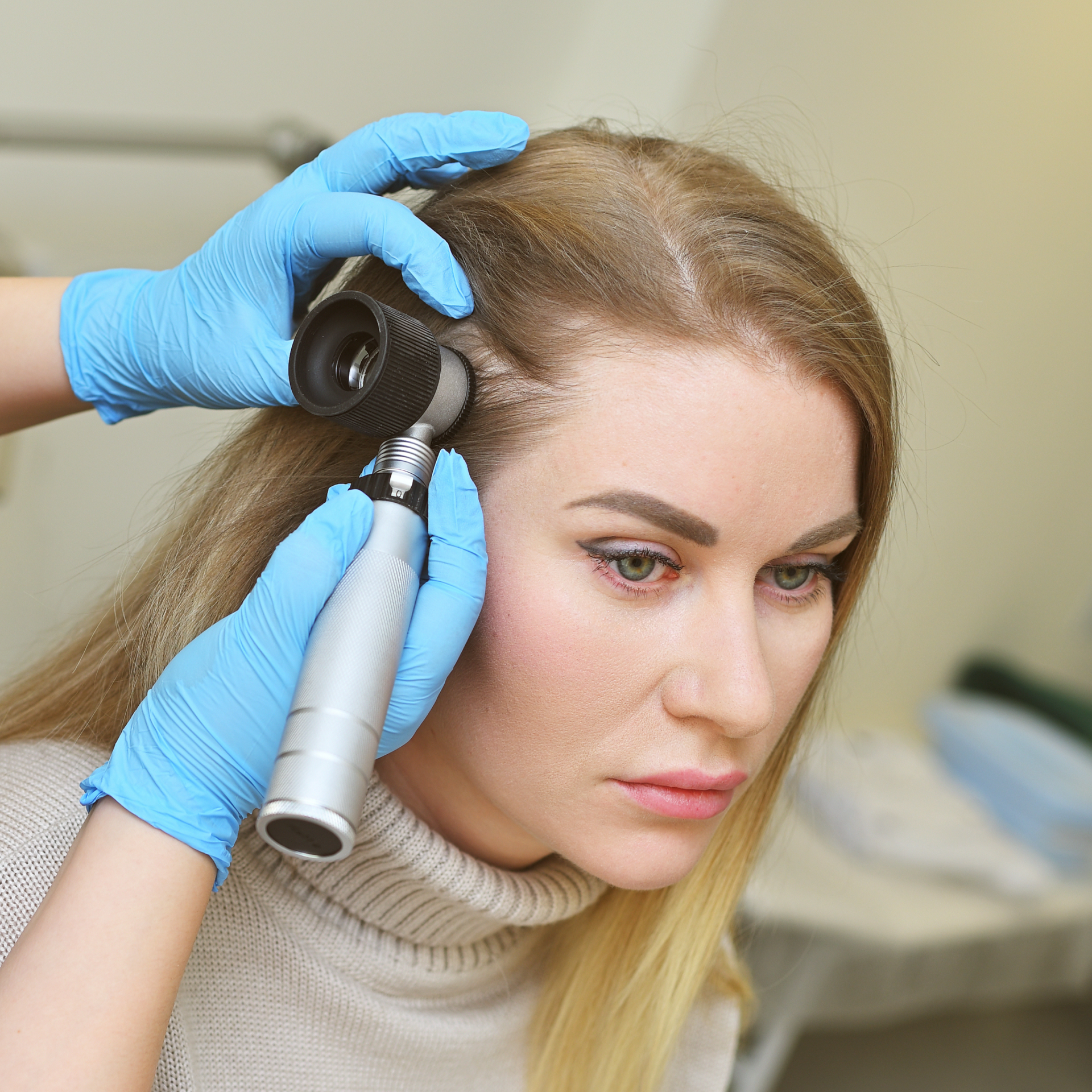 A woman examining hair thinning at her parting